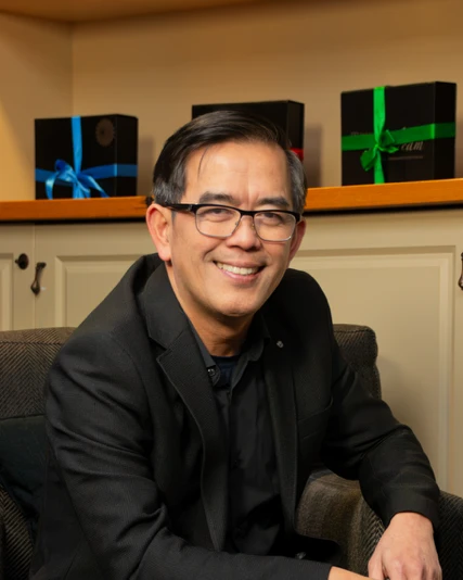 Dang Nguyen, coach at Lotus Life Coaching, smiling, wearing a dark jacket and glasses.