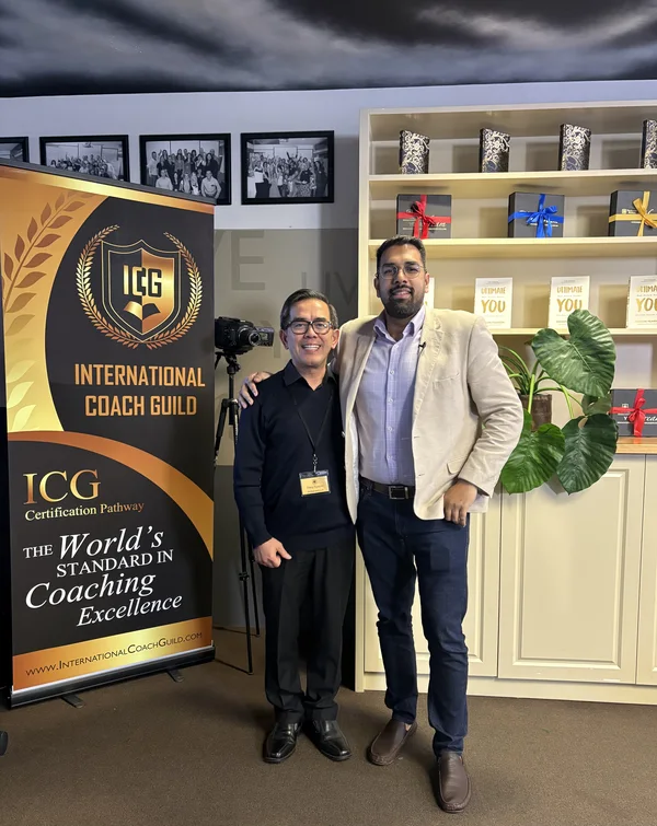Dang Nguyen standing beside an International Coach Guild banner with Rashid Mubashir.